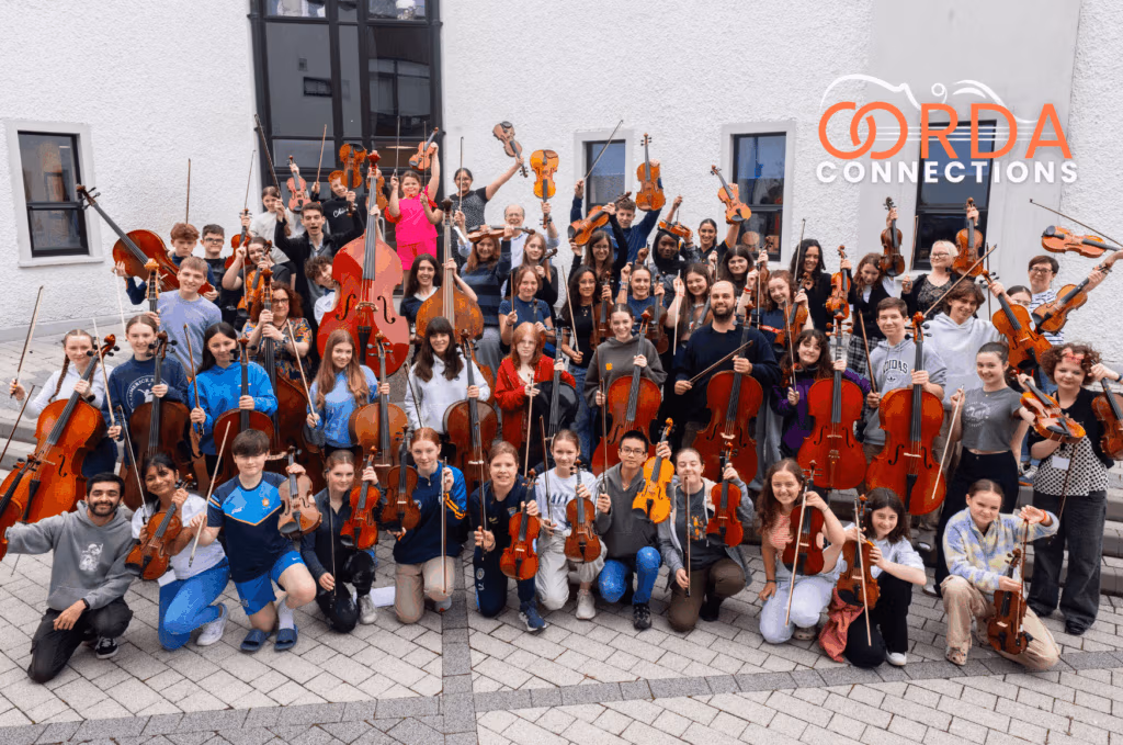 Corda Connections participants and musician educators gathered together outdoors with their violin, cello and viola and double bass at Dundalk Grammar School.